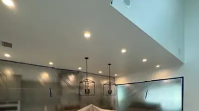 A kitchen undergoing renovation, with cabinets, appliances, and the island covered in protective plastic. Photo