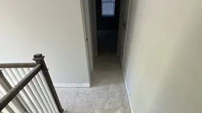 A hallway with light walls and unfinished concrete flooring awaits new installation. Photo