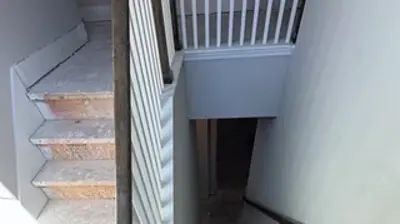 An unfinished indoor staircase shows steps going up to the left and down to the right, with bare subflooring visible. Photo