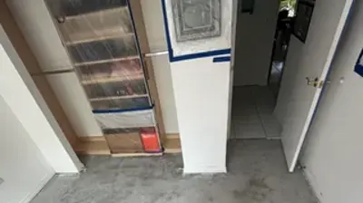 A room with a newly applied gray floor coating, showing an uneven, textured finish. Photo