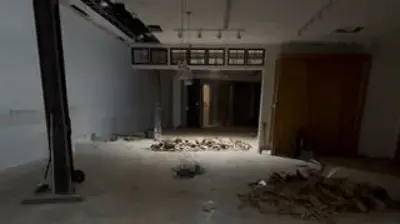 An indoor shot shows a large, empty space with a concrete floor covered in piles of debris. Photo
